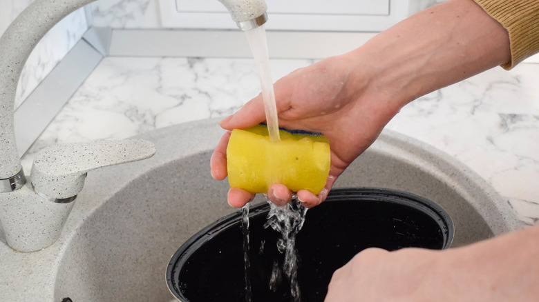 Person cleaning a slow cooker bowl in sink