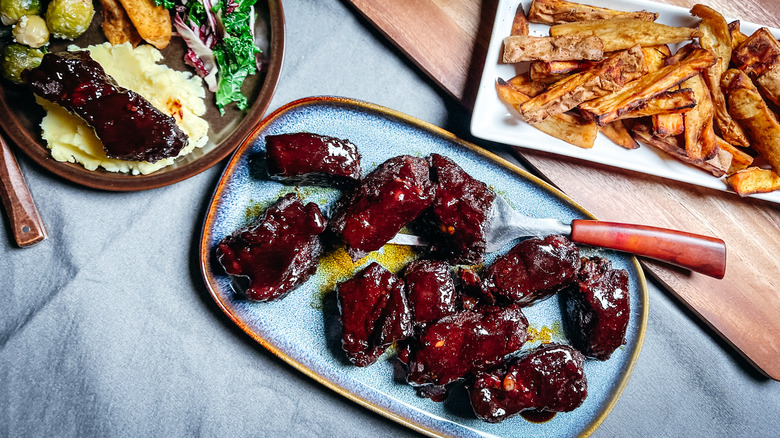 Smoky sweet barbecue beef short ribs on platter with sweet potatoes