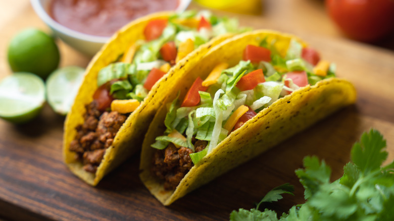 Two hard shell tacos on a wooden board