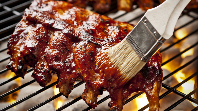 brushing barbecue sauce on meat