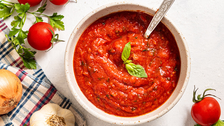 Bowl with tomato sauce; fresh tomatoes, parsley, onion, and garlic on the side 