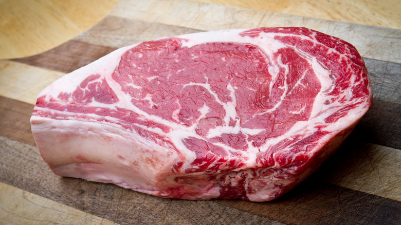 Raw ribeye on a wooden board.