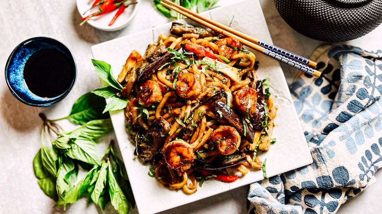 Shrimp and eggplant stir-fry on plate with chopsticks and garnish