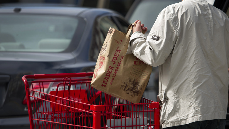 Person loading Trader Joe's paper bags into car. 