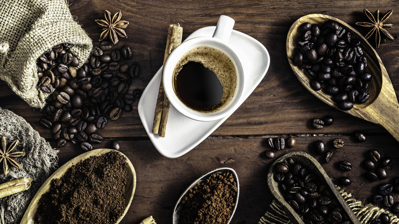 Coffee cup on vintage table and an assortment of ground and roasted coffee.