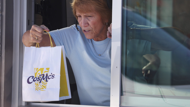 CosMc's worker handing bag through the drive-thru window.