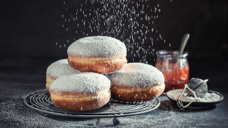 A pile of pazcki sprinkled with powdered sugar.