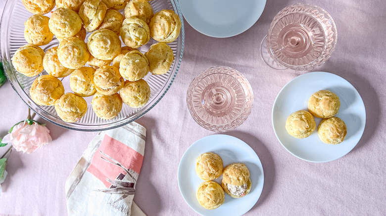 Valentine's Day gruyere and crab gougères on serving platter with wine glasses