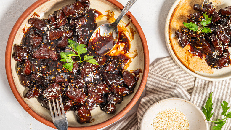 Sticky soy steak bites on a plate with fork and spoon in it