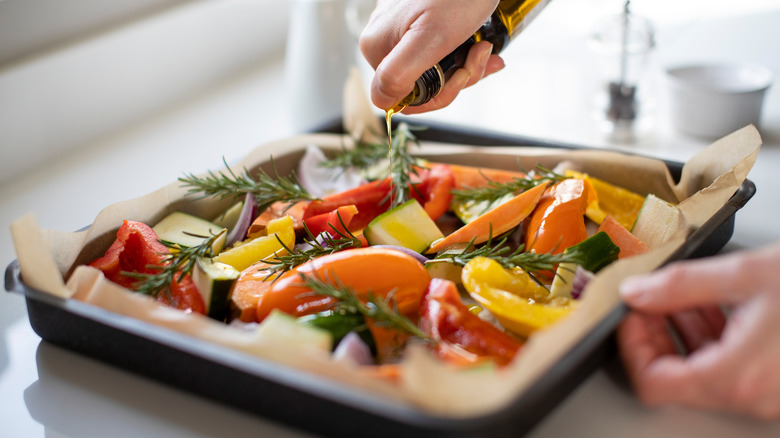 Person pouring oil on vegetables