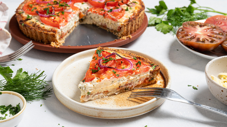 Slice of roasted tomato pie on a plate and the rest of the pie in the background