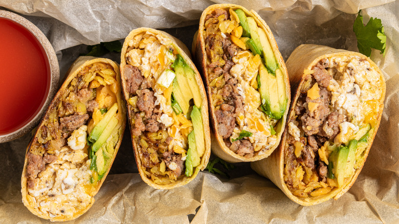 breakfast burritos with eggs, sausage, and avocado, sliced and standing