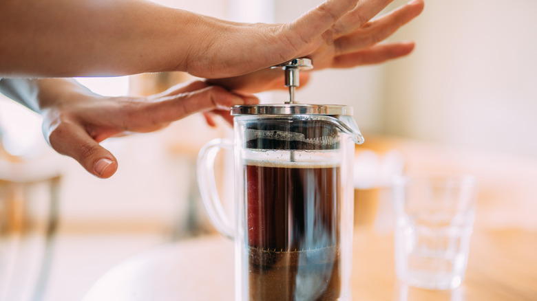 tan hands pushing French press