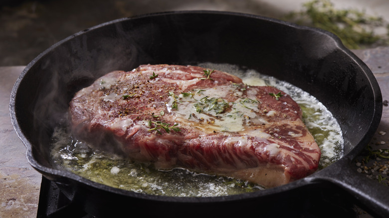 A steak pan frying in butter