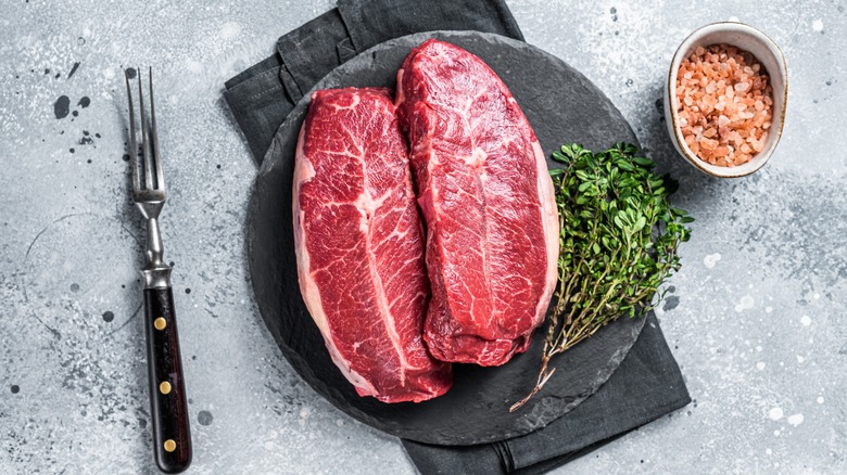 Two cuts of oyster blade steak on a plate with herbs