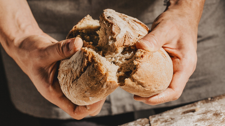 man tearing fresh soft bread