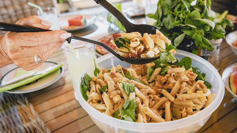 Woman serving summer pasta salad