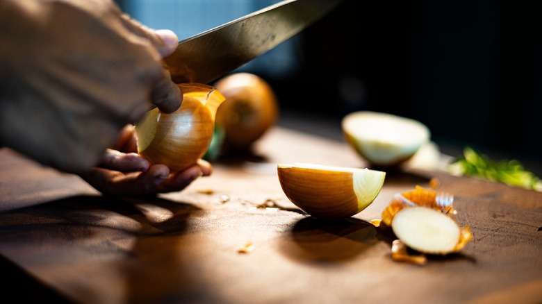 person peeling onion with knife