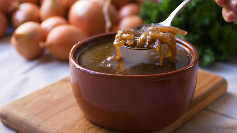 Spoon raised over bowl of french onion soup.