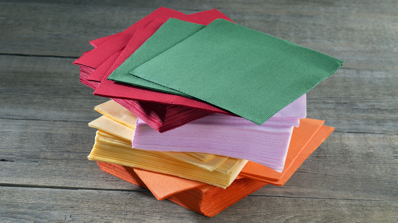 Stack of colorful paper napkins on wooden background