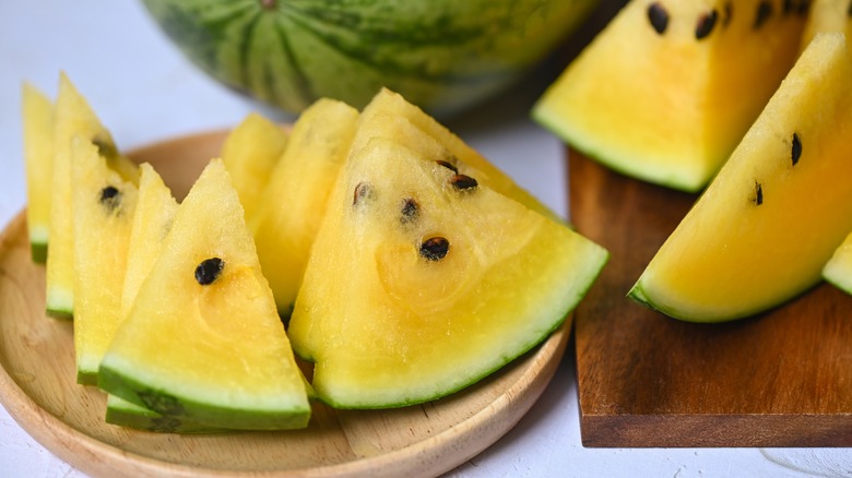 Sliced yellow watermelon on board