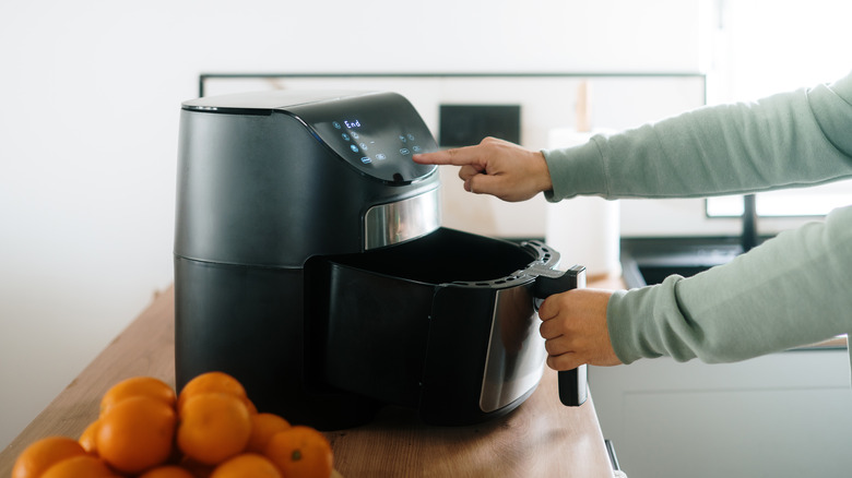 Hands touching an air fryer