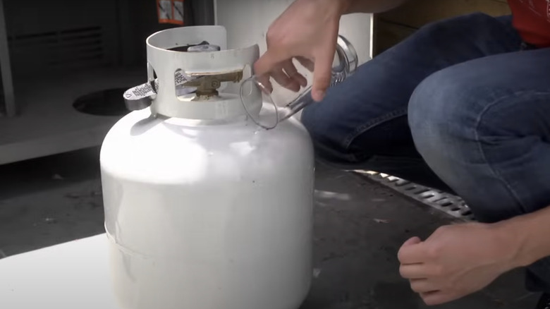 Person pouring water on tank.