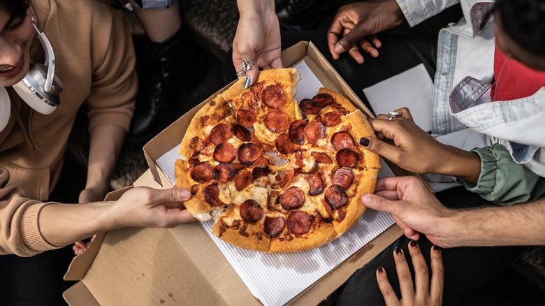 Hands grabbing at pizza