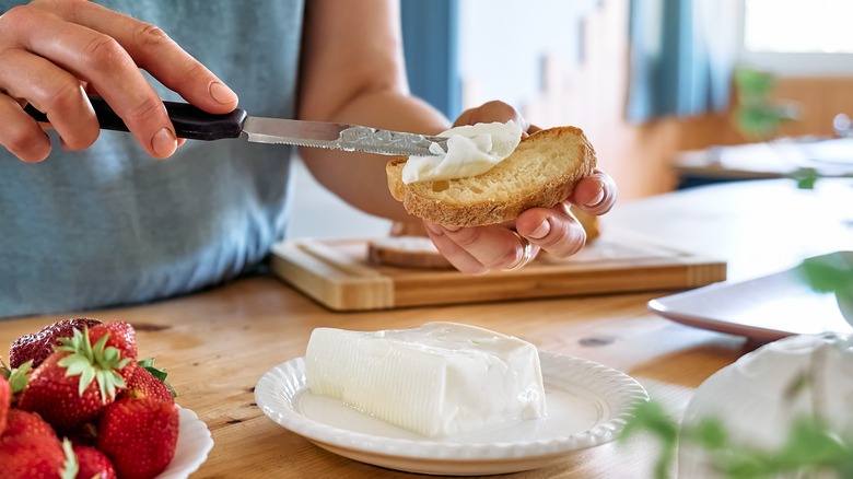 Hands spreading cheese on sourdough