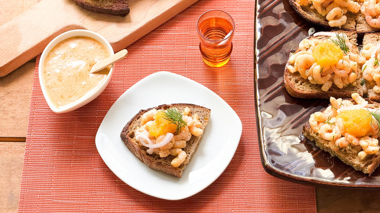 Shrimp salad toast Skagen on plate and platter with sauce