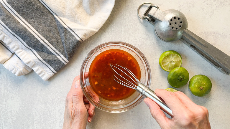 Whisking marinade for grilled flank steak tacos with lime halves and juicer