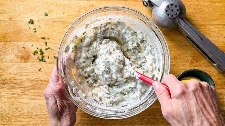 Mixing together greek yogurt, arugula, fennel, and seasoning for salmon dill pasta salad