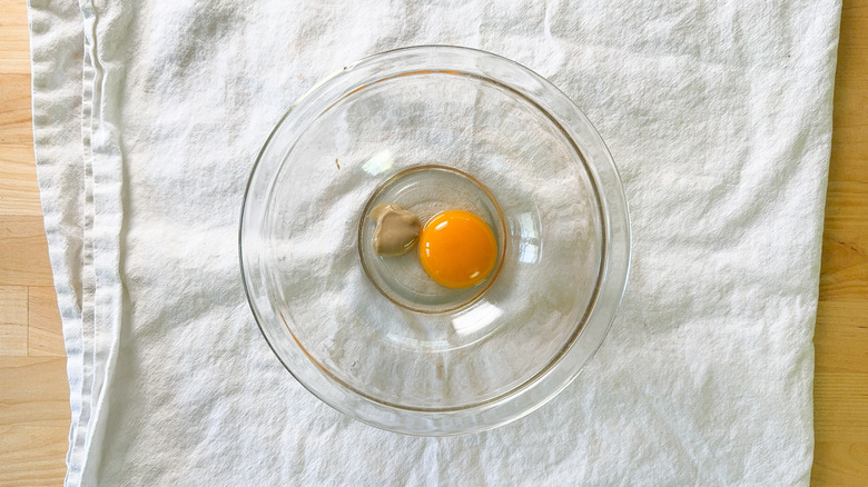 Mayonnaise ingredients in glass bowl on folded towel