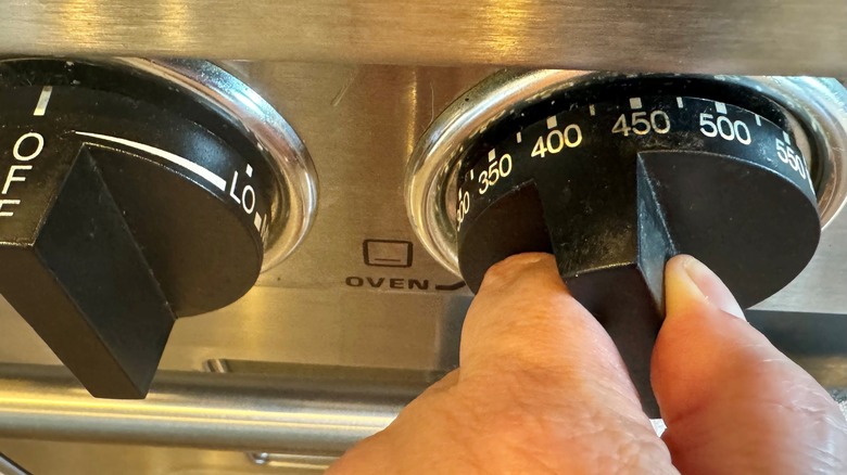 hand touching oven temperature gauge