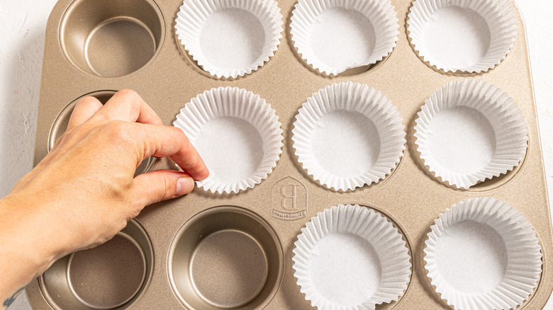 Placing paper liners to a cupcake tin