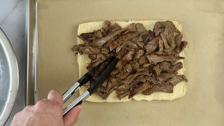 hand putting meat on bread