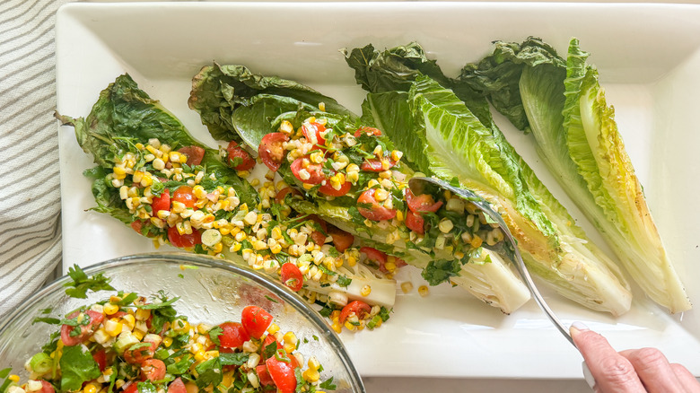 hand adding topping romaine