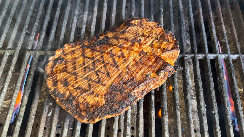 Grilled flank steak on gas grill grates