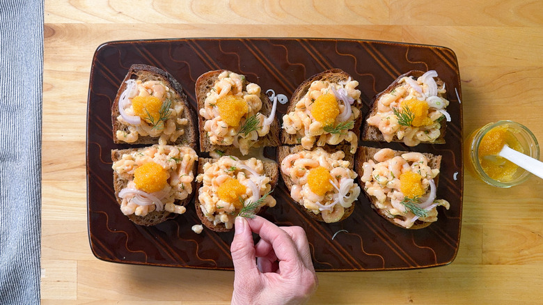 Putting caviar and dill garnishes on shrimp salad toast Skagen on serving platter