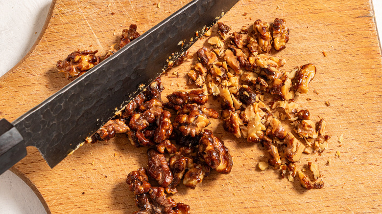 knife chopping walnuts on wooden board