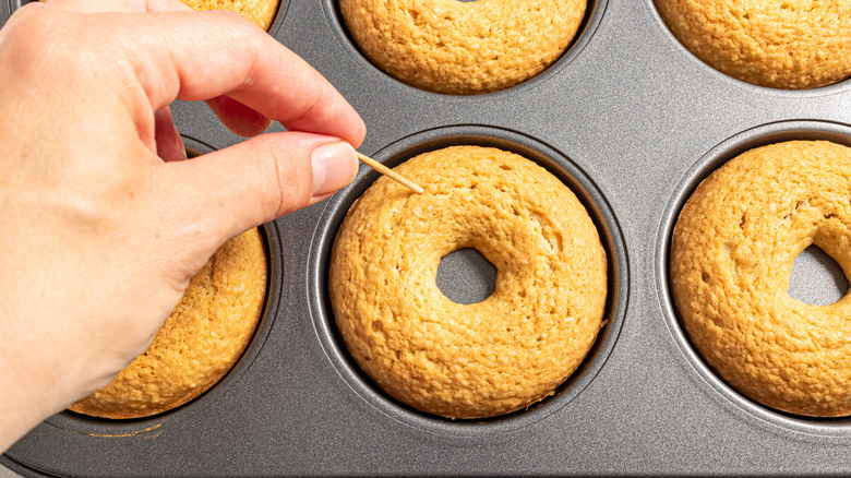 Checking baked donuts with toothpick for doneness